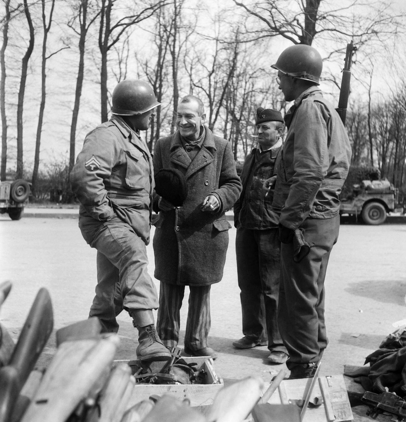 #1 French prisoner commander Bellon chats with American soldiers in front of a pile of weapons belonging to the SS at Buchenwald Nazi camp, April 12, 1945.
