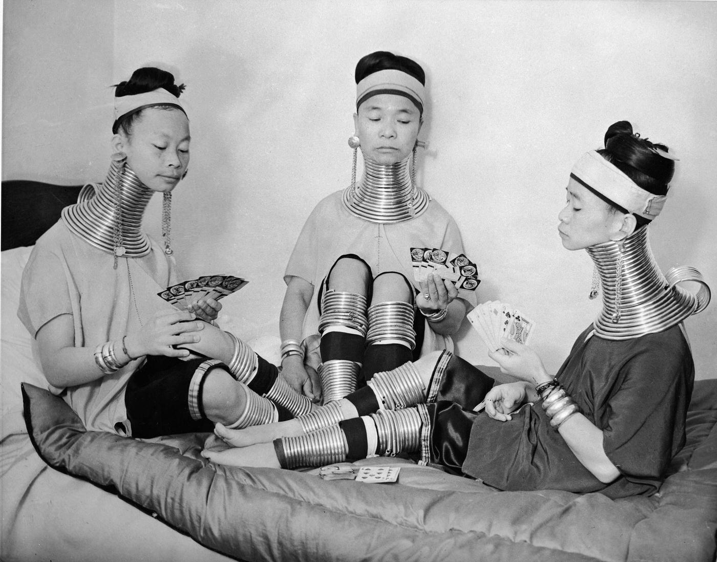 #10 Three Burmese women from a circus playing cards while wearing brass neck and leg rings, London, 1935.