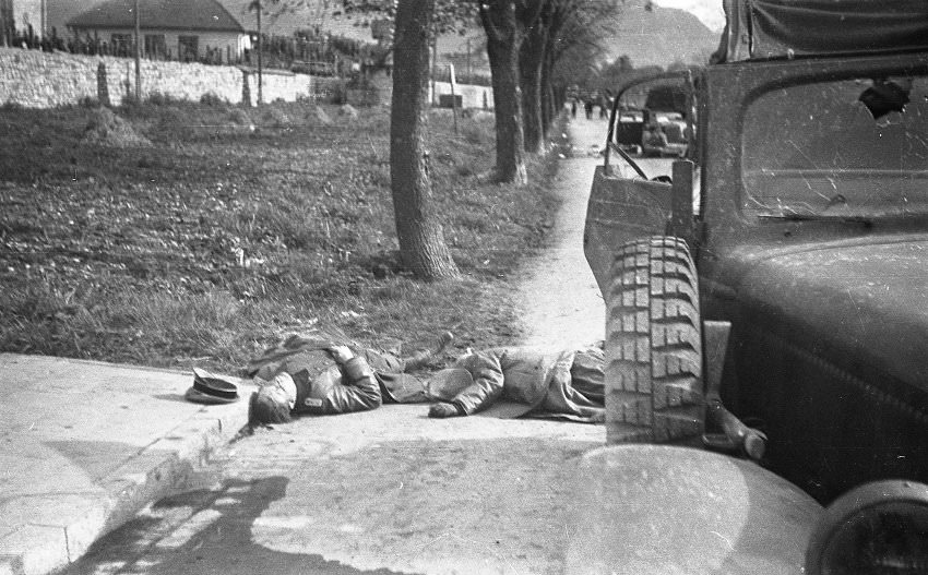 #13 Somewhat later, the photographer apparently left his position in the camp to get a closer look at the two dead German officers. The bodies by this point had been moved from the center to the side of the street.