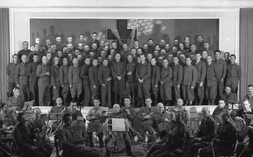 #7 A group of officers poses on the stage of the camp theater, with the orchestra in the foreground.