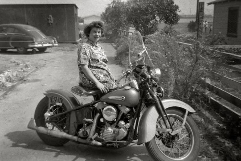 #33 Young mother posing with the family Harley-Davidson in California, 1953
