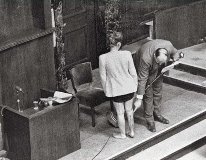 #7 Alexander points at scars on the leg of Polish survivor Jadwiga Dzido, who endured sulfanilamide experiments at Ravensbruck concentration camp.
