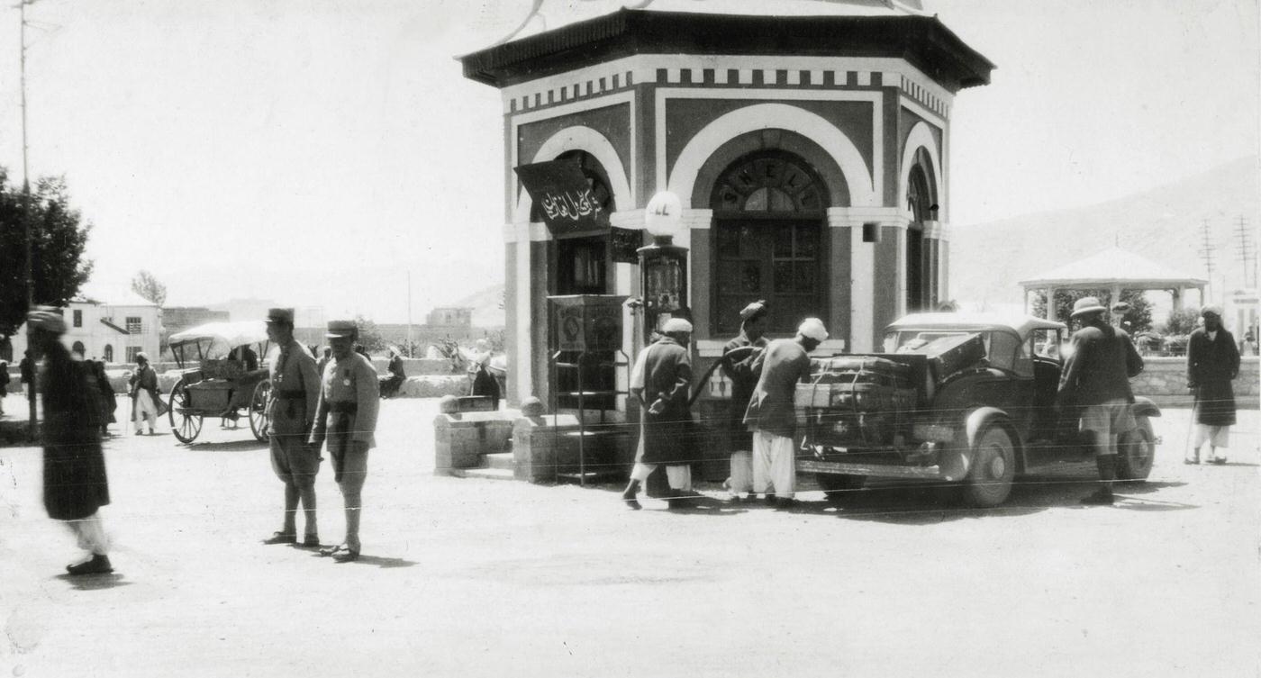 #14 People at a petrol filling station on a Kabul street, circa 1950.