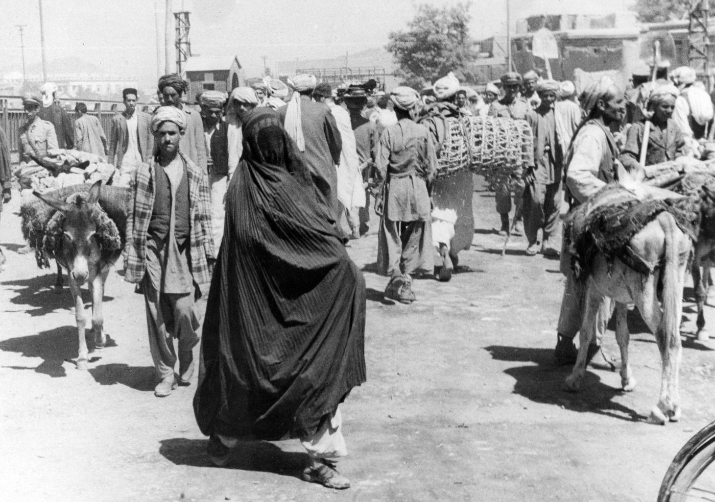 #16 Woman in a full “burkah” on a street full of men, circa 1950s.