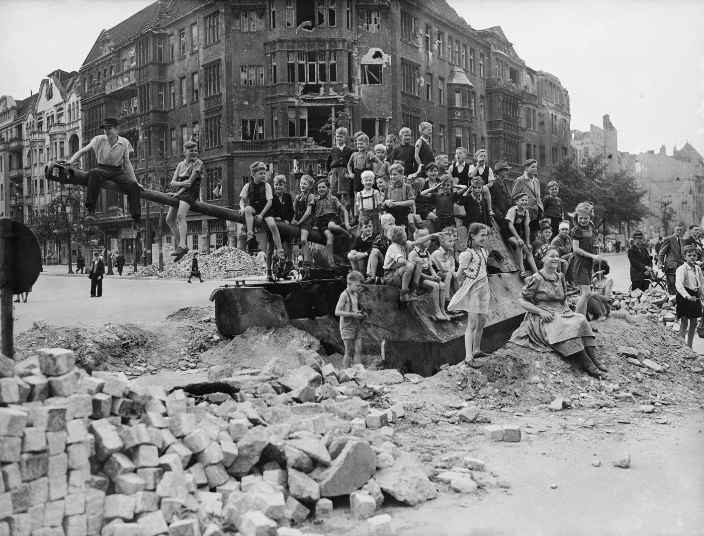 #56 German children playing on a tank in a bomb-damaged part of Berlin, 1945.