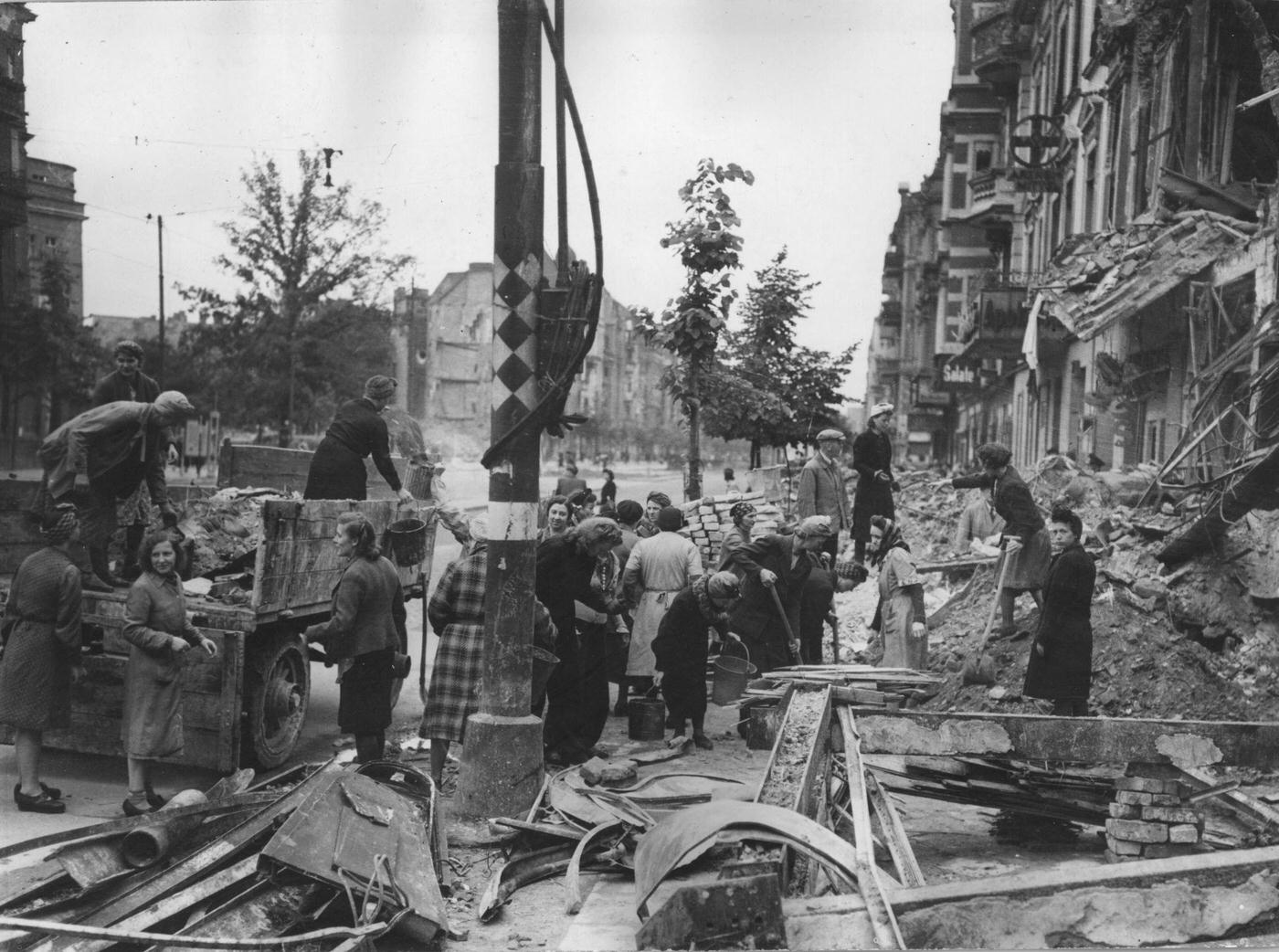 #57 German women clearing away debris from a street in the bomb-devastated business center of Berlin, 1945.