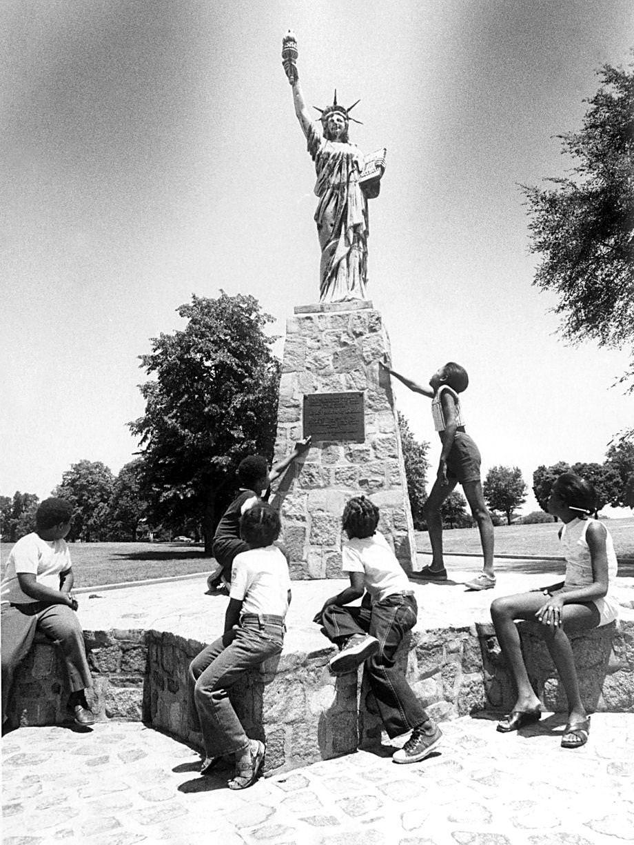 #88 Children sat around the small Statue of Liberty in Chimborazo Park in Richmond, 1975.