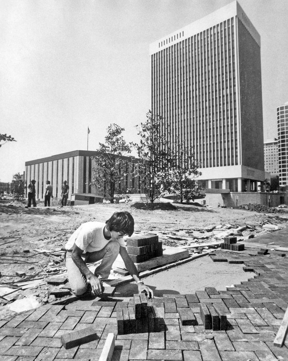 #8 Terry Woo set bricks for a walkway as construction of Kanawha Plaza in downtown Richmond continued, 1979.