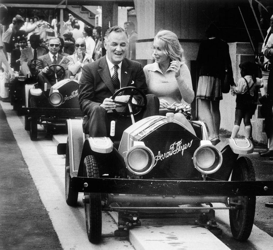 #77 Gov. Mills E. Godwin Jr. and Mrs. August Busch III rode the lead car around the Le Mans track in the French village of the new Busch Gardens: The Old Country theme park near Williamsburg, 1975.