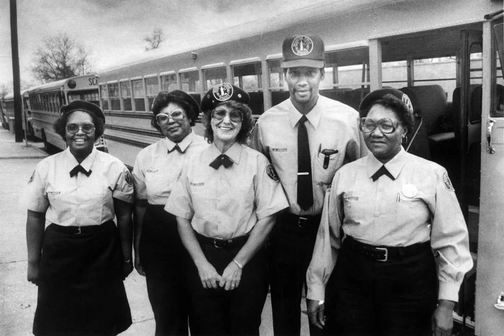 #83 A group of Richmond school bus drivers modeled new uniforms, which included light blue shirts, navy slacks or skirts, berets or caps, and jackets and ties, 1982