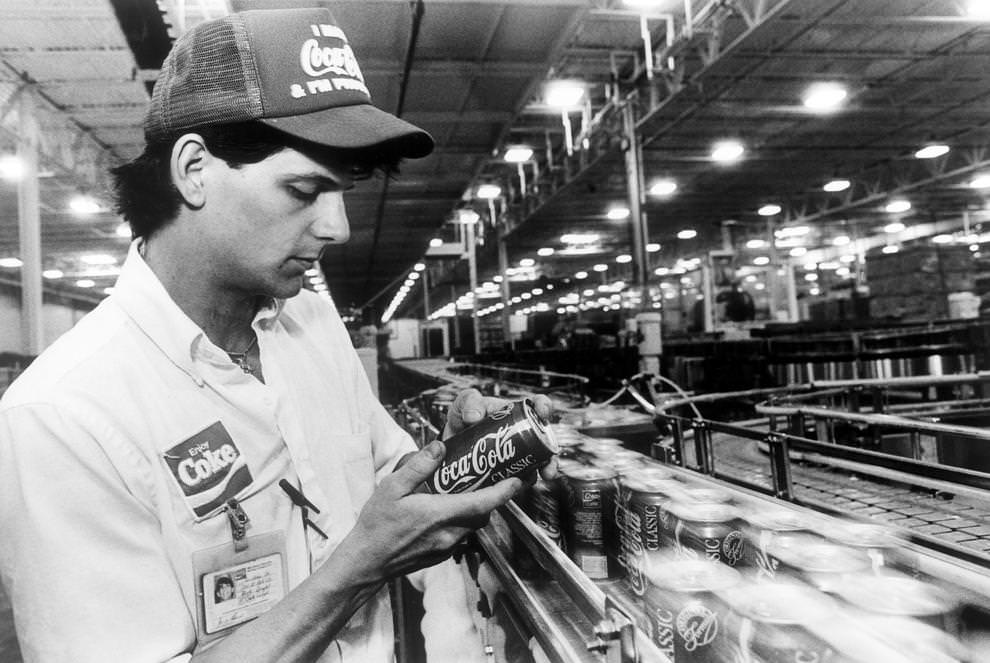 #28 Quality assurance technician Blake Dingler examined Coca-Cola cans as they moved through Mid-Atlantic Coca-Cola Bottling Co.’s new production plant in eastern Henrico County, 1990.