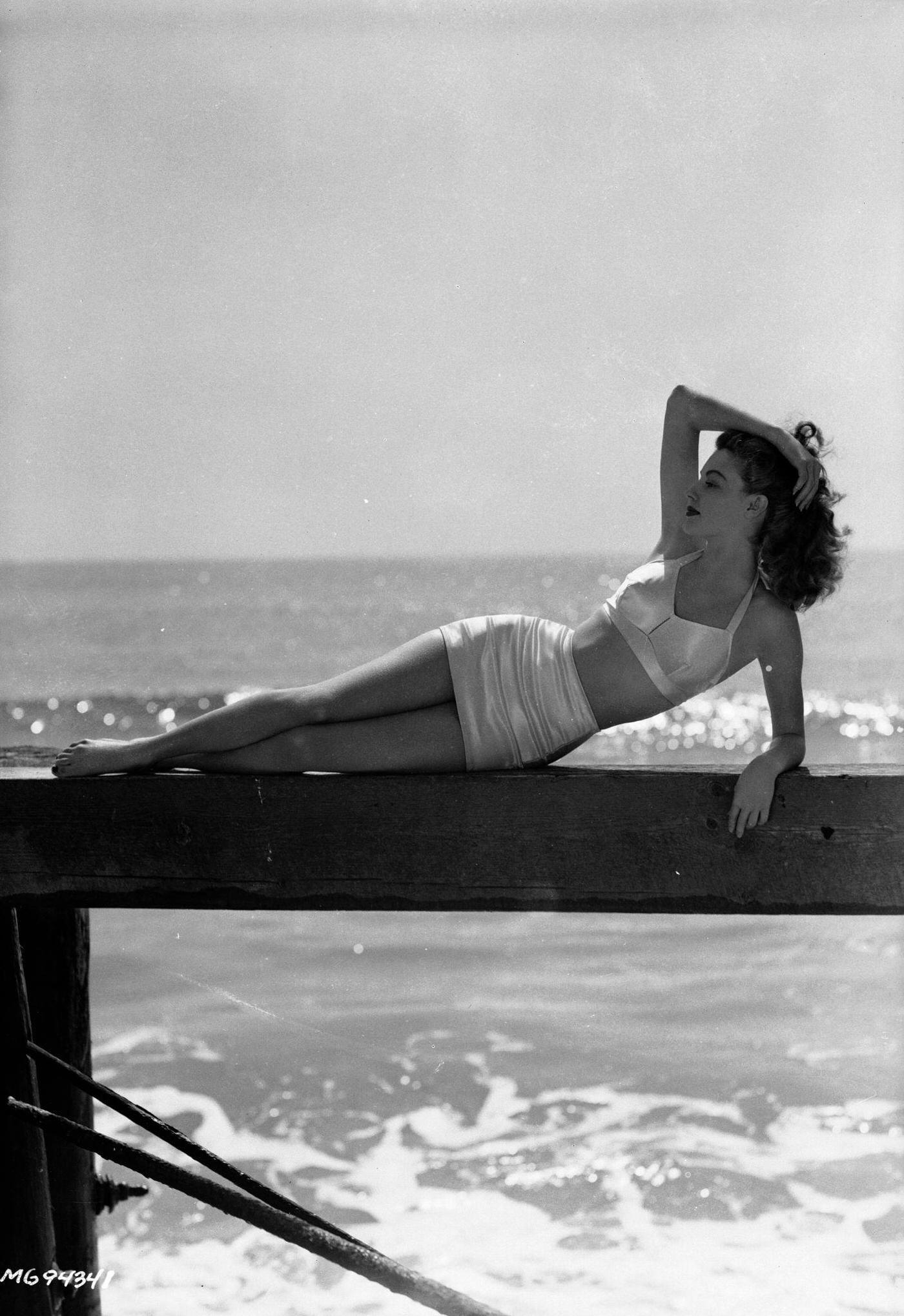 #23 Actress Ava Gardner lounging on a wooden jetty in an elegant bikini, March 1943.