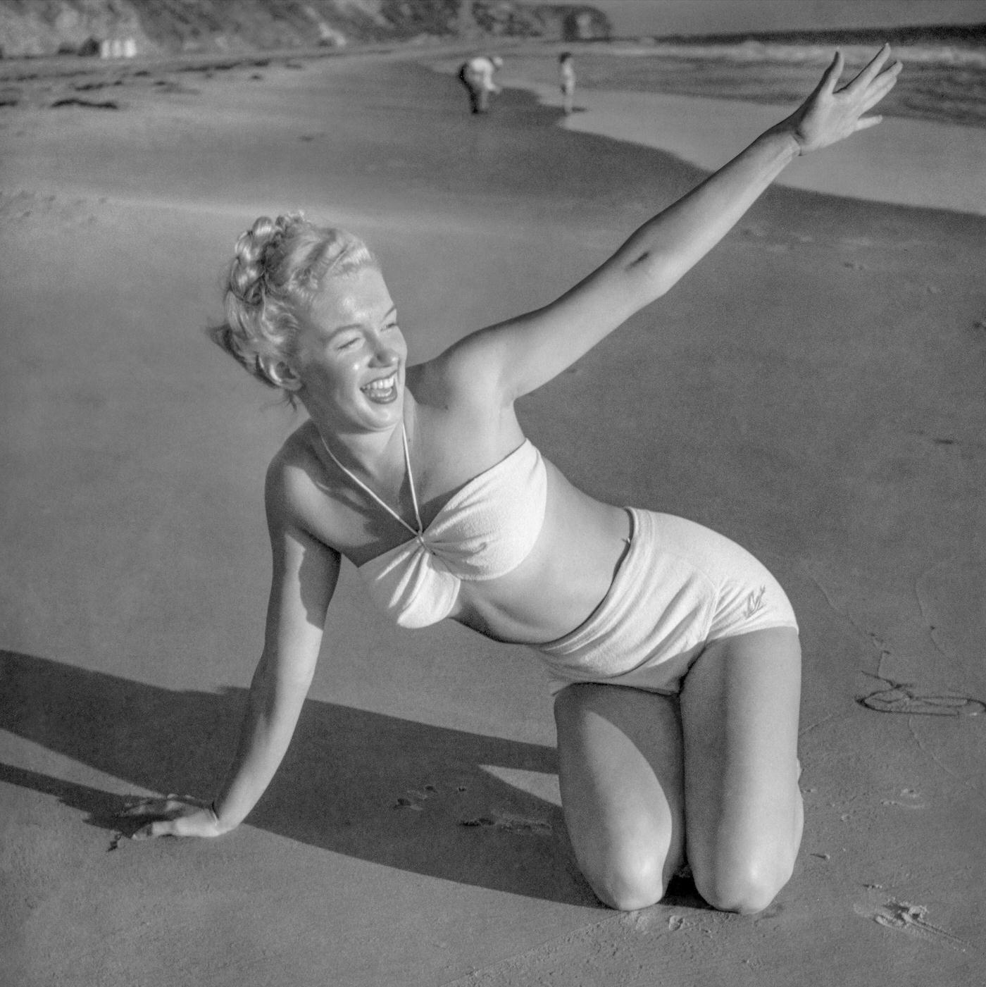 #46 Marilyn Monroe posing on a beach in a two-piece swimsuit, Malibu, California, 1946.