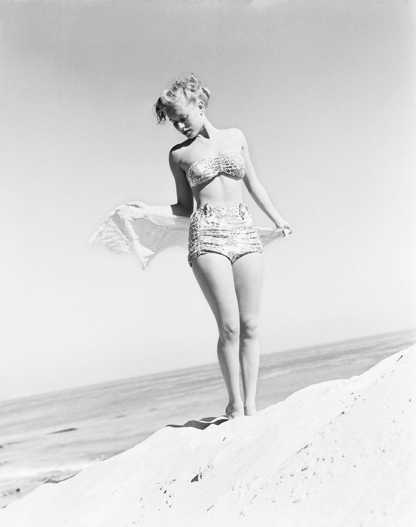#52 Model Fran Cooper wearing a patterned bikini on the beach, 1948.