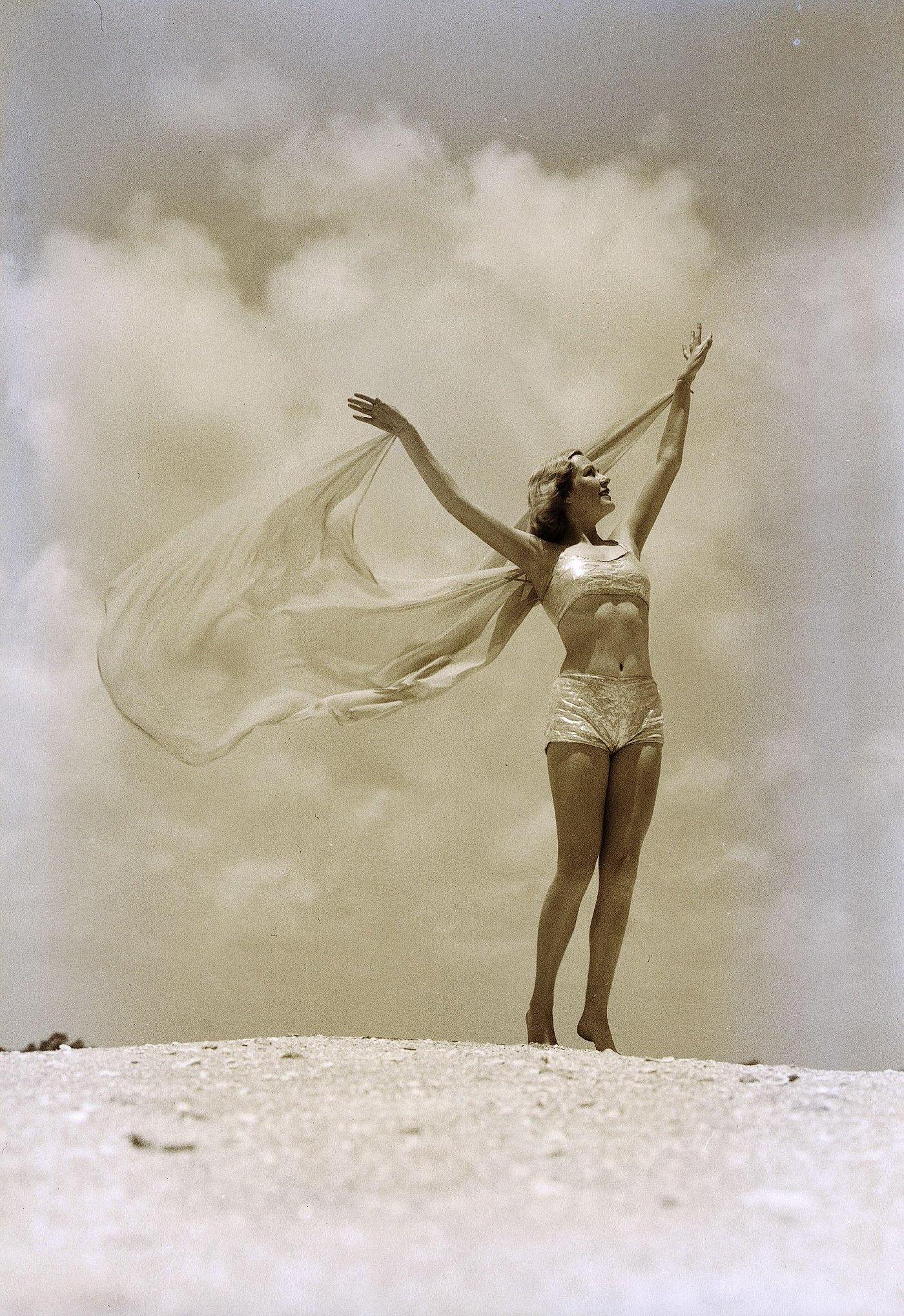 #7 Woman in swimsuit with arms outstretched, posing on a rocky embankment