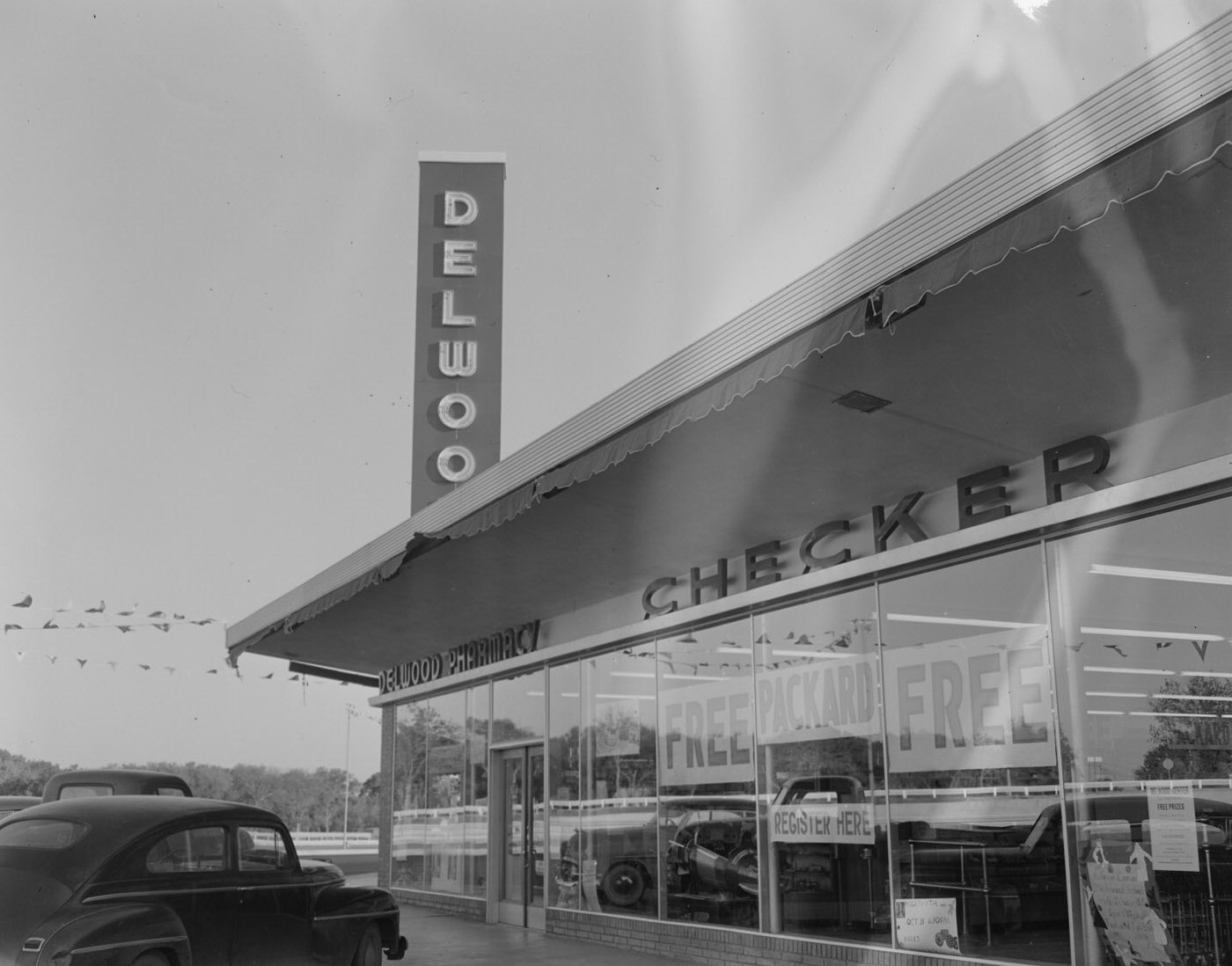 #54 Delwood Pharmacy Building with Parked Cars, 1953
