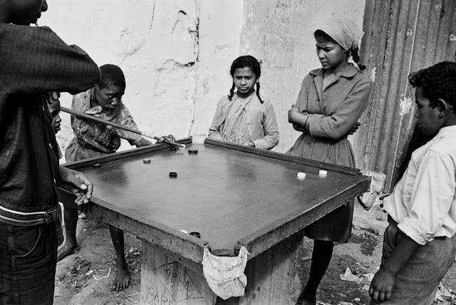 #25 Hawking fresh vegetables, fruit, or fish, was big business in the area, and beyond. When not in use, hawkers’ barrows were stashed along pavements. The wheels were removed to prevent unauthorised use or theft by rivals. District Six, Cape Town, South Africa.
