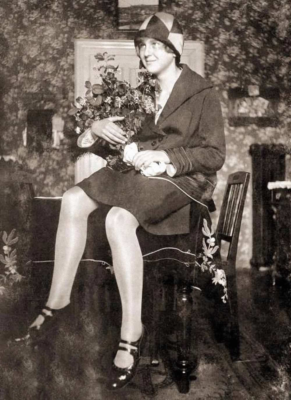 #65 Eva Braun sitting on a table in the living room at her parent’s house in Munich, Germany, 1929. She was staying with her family after finishing her education at a trade school; later that year, she met Hitler at Hoffmann’s photo studio.