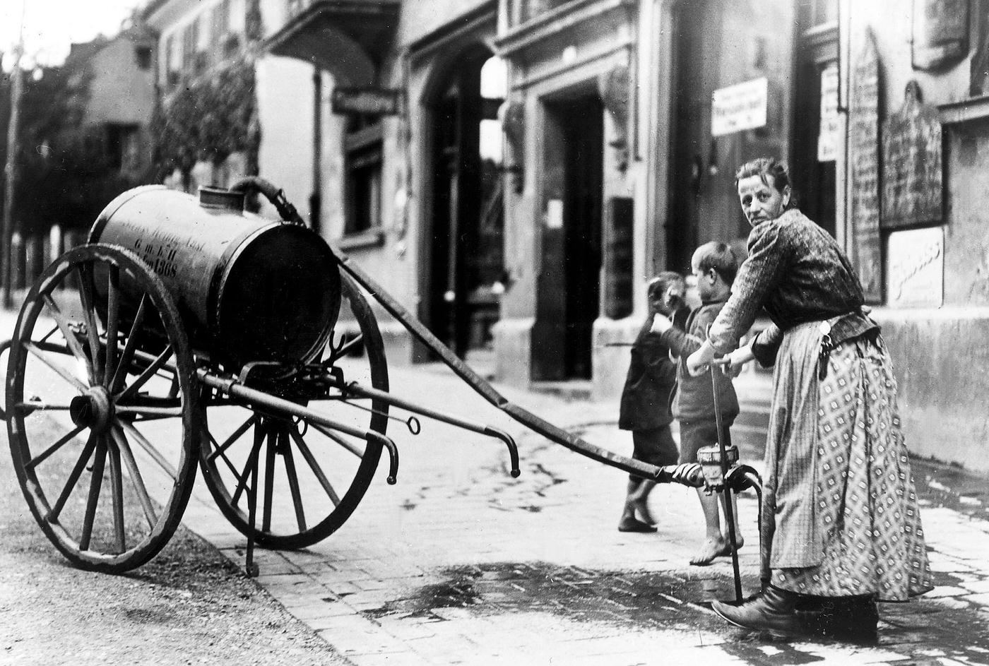 #20 Woman refilling water container, Munich, Germany, around 1900.