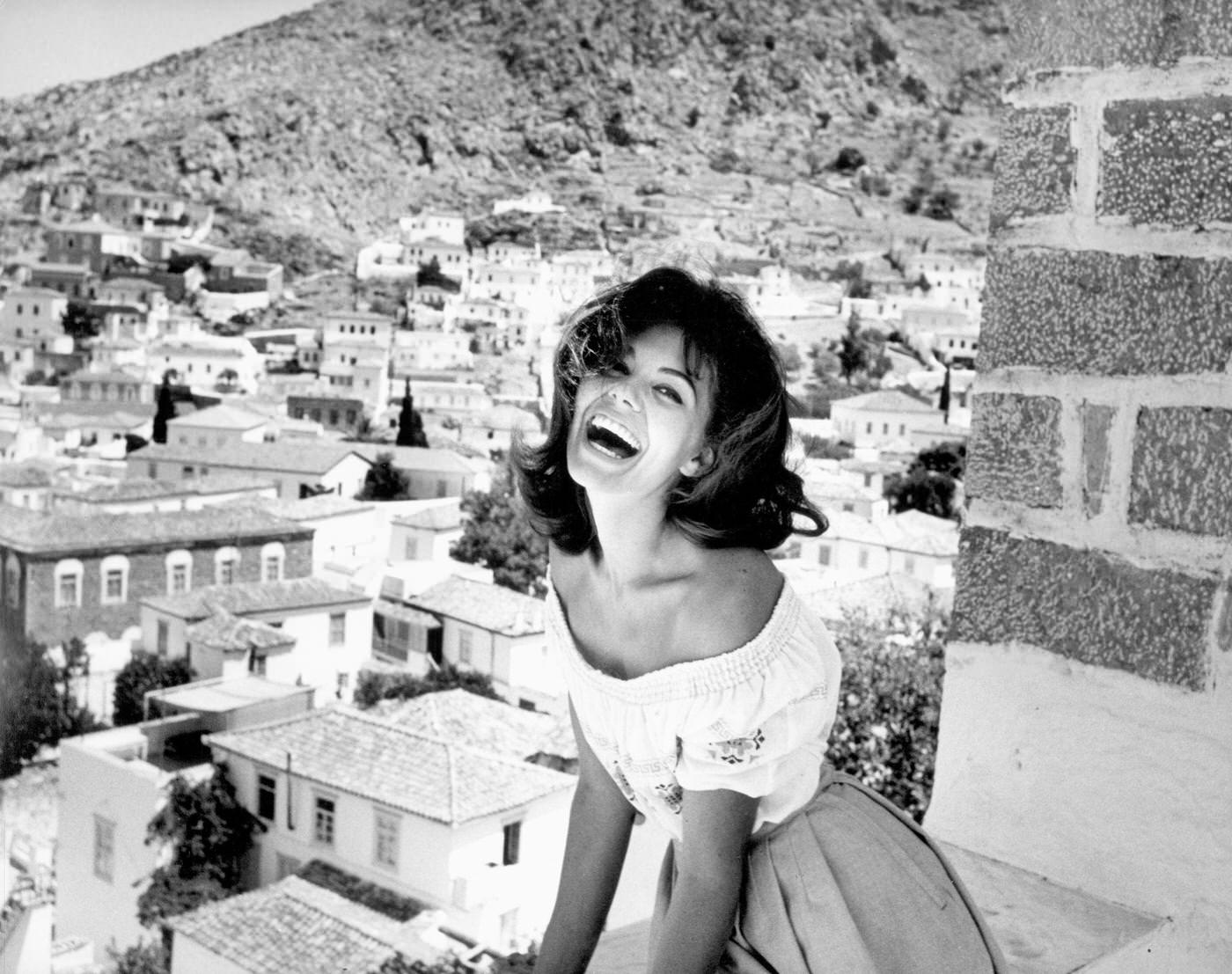 #66 Giorgia Moll laughing on a balcony, filming ‘Island of Love,’ Greece, 1962
