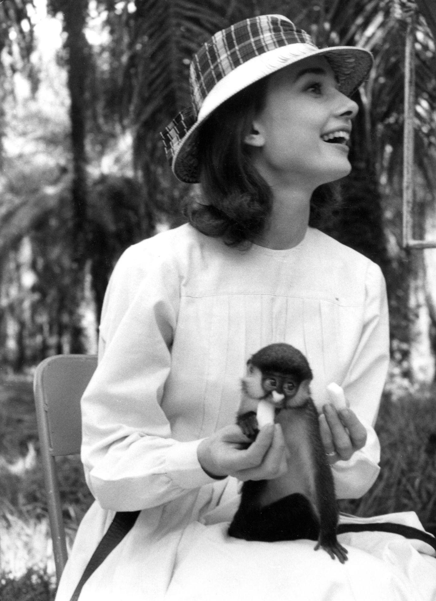#82 Actress Audrey Hepburn laughs while feeding a monkey on her lap in Kisangani, Congo, 1958.