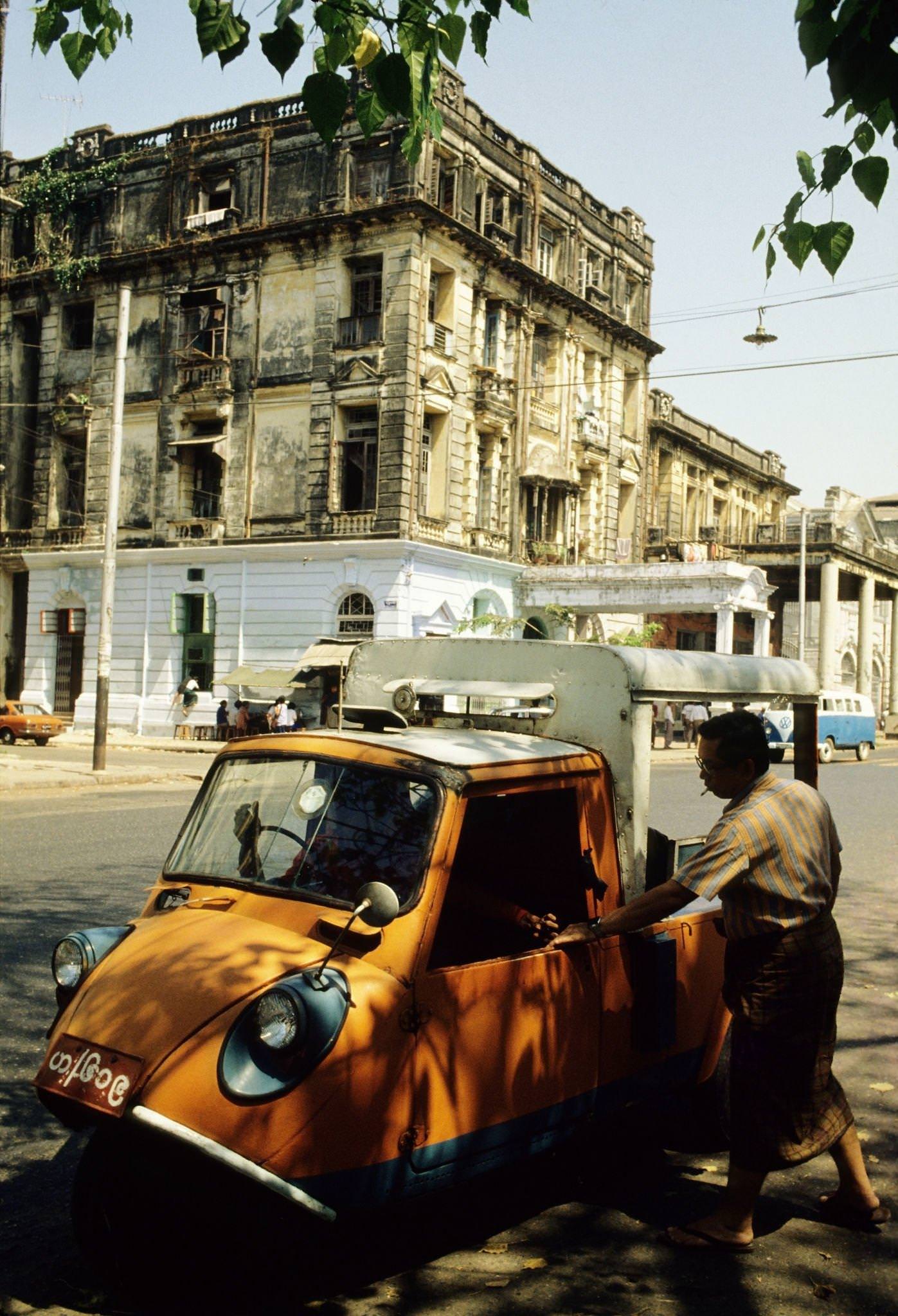 #37 Orange-Coloured Auto Rickshaw Picks Up a Male Passenger in Rangoon, Burma, 1985