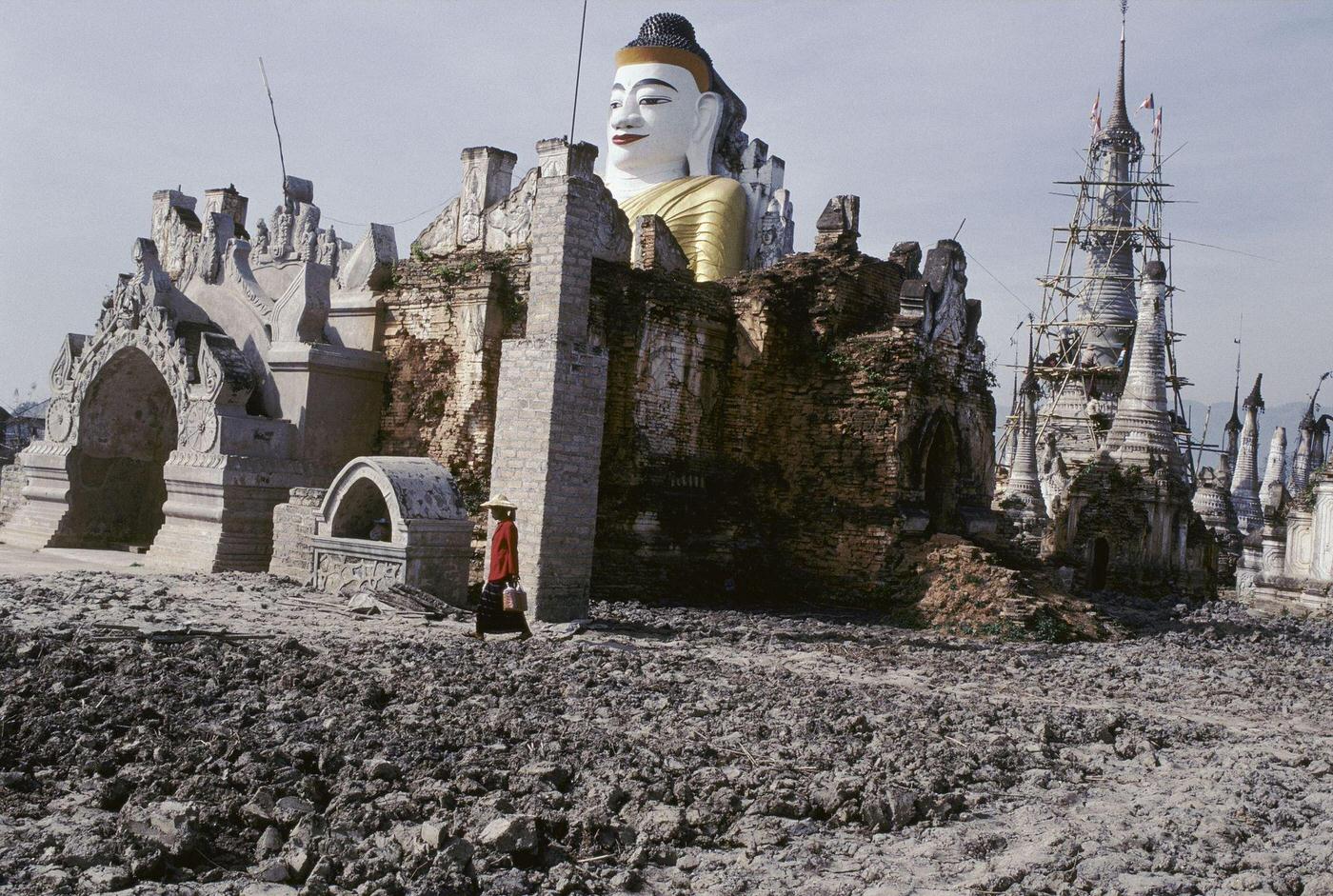 #57 Nyaung Shwe, Myanmar – Woman Passing a Statue of Buddha Near Inle Lake, 1980s