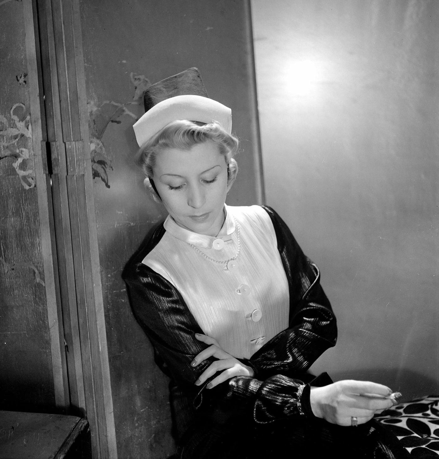 #26 A fashion model sits and smokes a cigarette wearing a hat designed by French fashion designer Jeanne Lanvin, Paris, 1935.