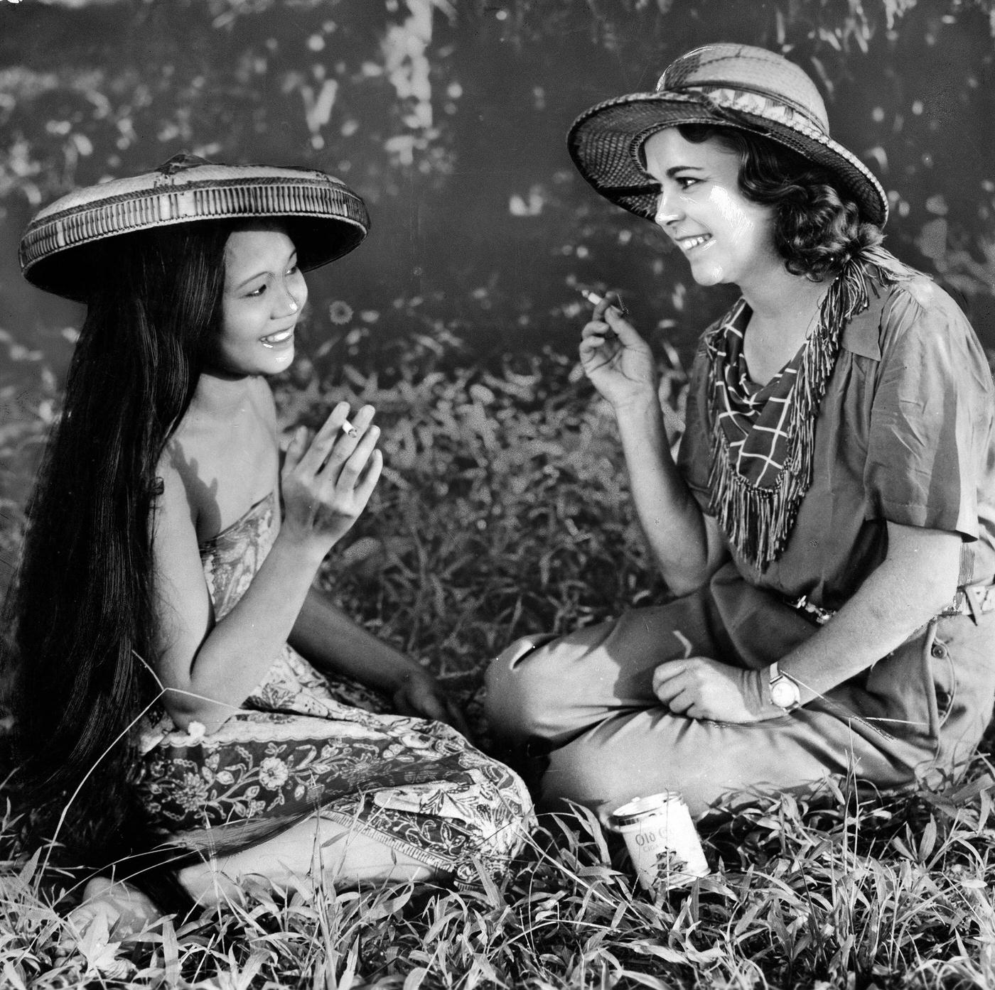 #76 Osa Johnson smoking a cigarette with a woman in traditional clothing, 1937
