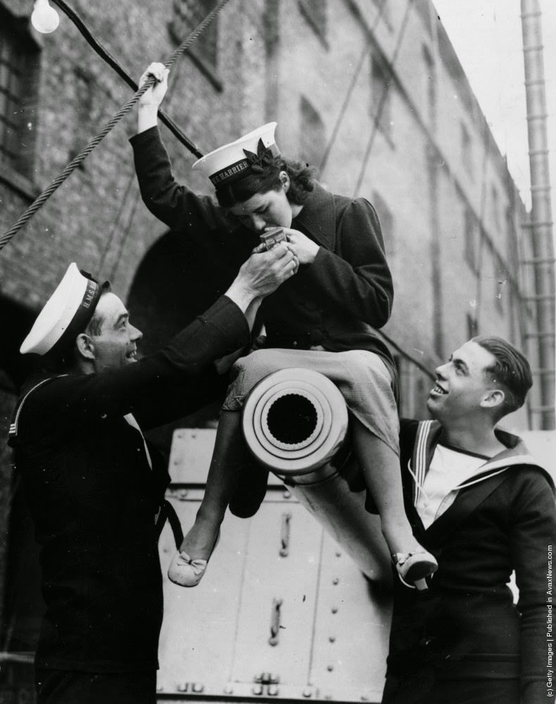 #1 A young female British Navy officer sitting astride a minesweepers cannon and lighting a cigarette whilst two officers look on, 5th June 1937