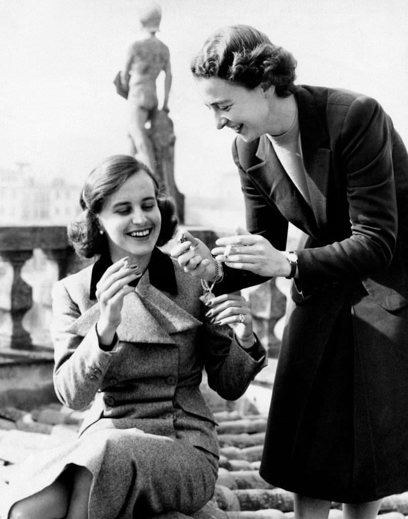 #26 On a terrace, Italian baroness Francesca Ricasoli lighting a cigarette to Italian artist, princess Giuliana Corsini, 1950s.