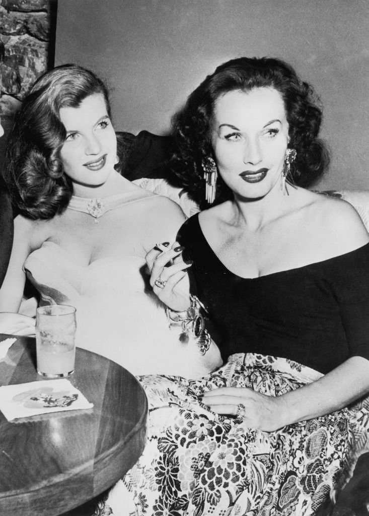 #42 French actress Corinne Calvet smoking a cigarette with Czechoslovakian actress Florence Marly at the World Film Favourite Festival, California, 1951.