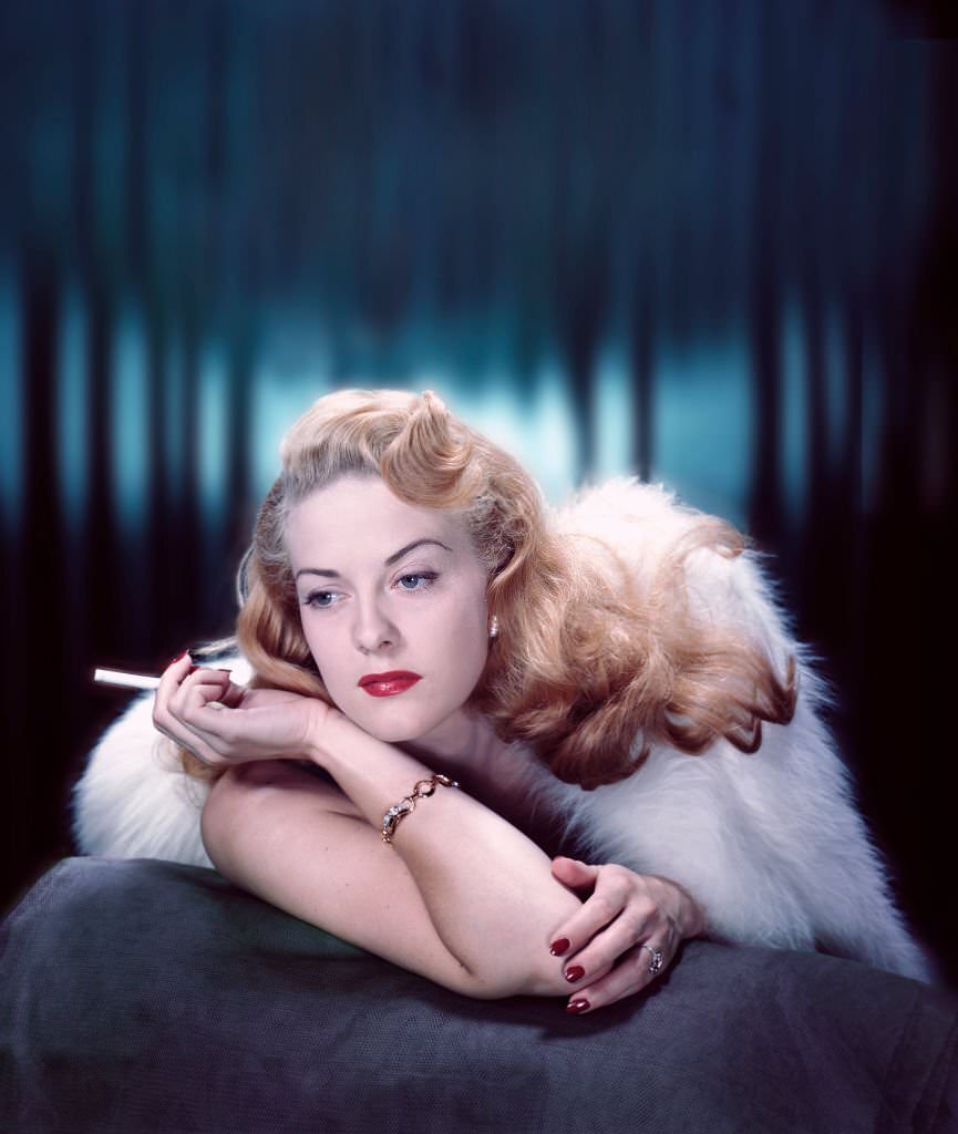 #69 Close-up portrait of a fashion model smoking under a fur wrap, 1955.