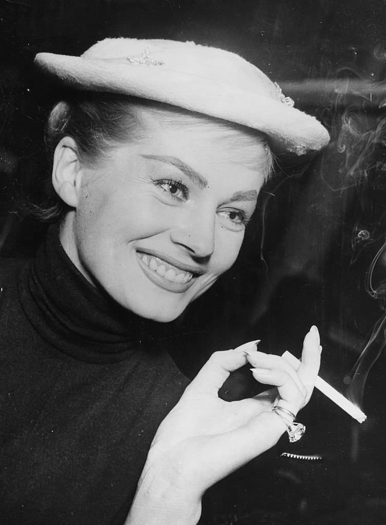 #79 Actress Anita Ekberg smoking a cigarette in Copenhagen, on the way to Malmo, Denmark, 1956.