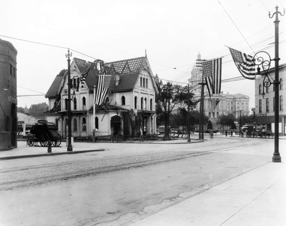 #33 Engine House Number One being dismantled at the corner of Colfax and Broadway, featuring stagecoach and flags, 1909.