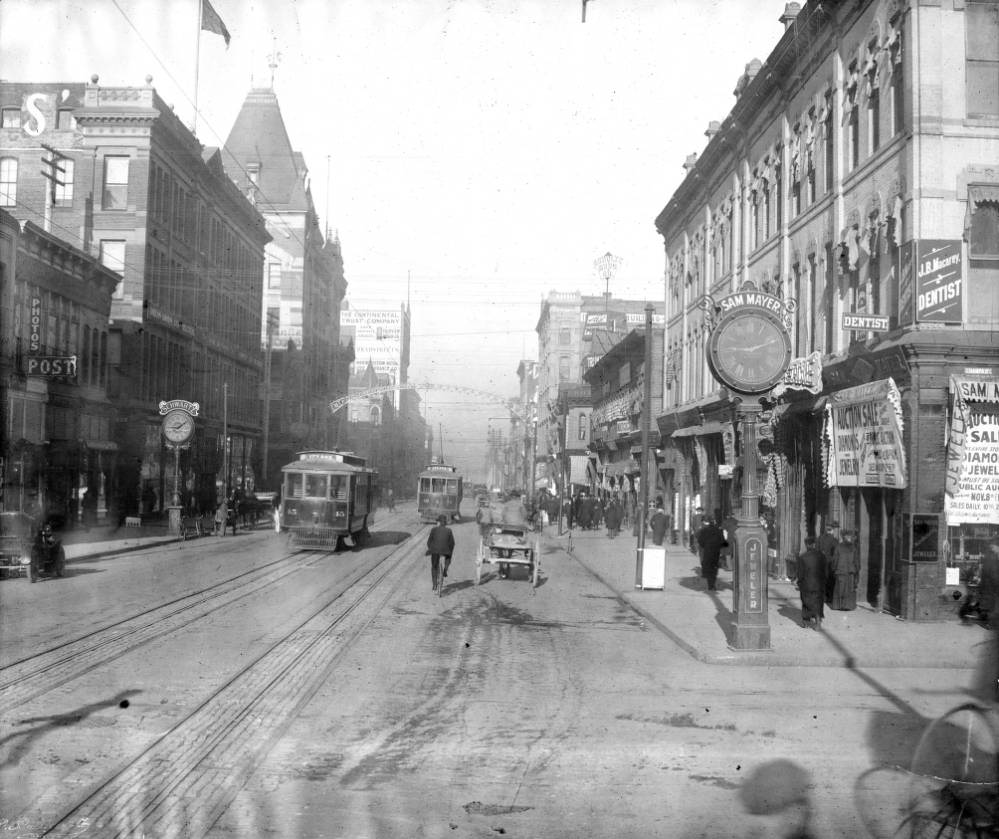 #64 Trolleys number 45 and 42 at 16th and Champa, featuring various business signs and traffic, 1905.