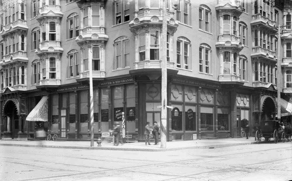 #67 Men shaking hands outside Albany Hotel, featuring railroad signs and a barbershop pole, 1900s