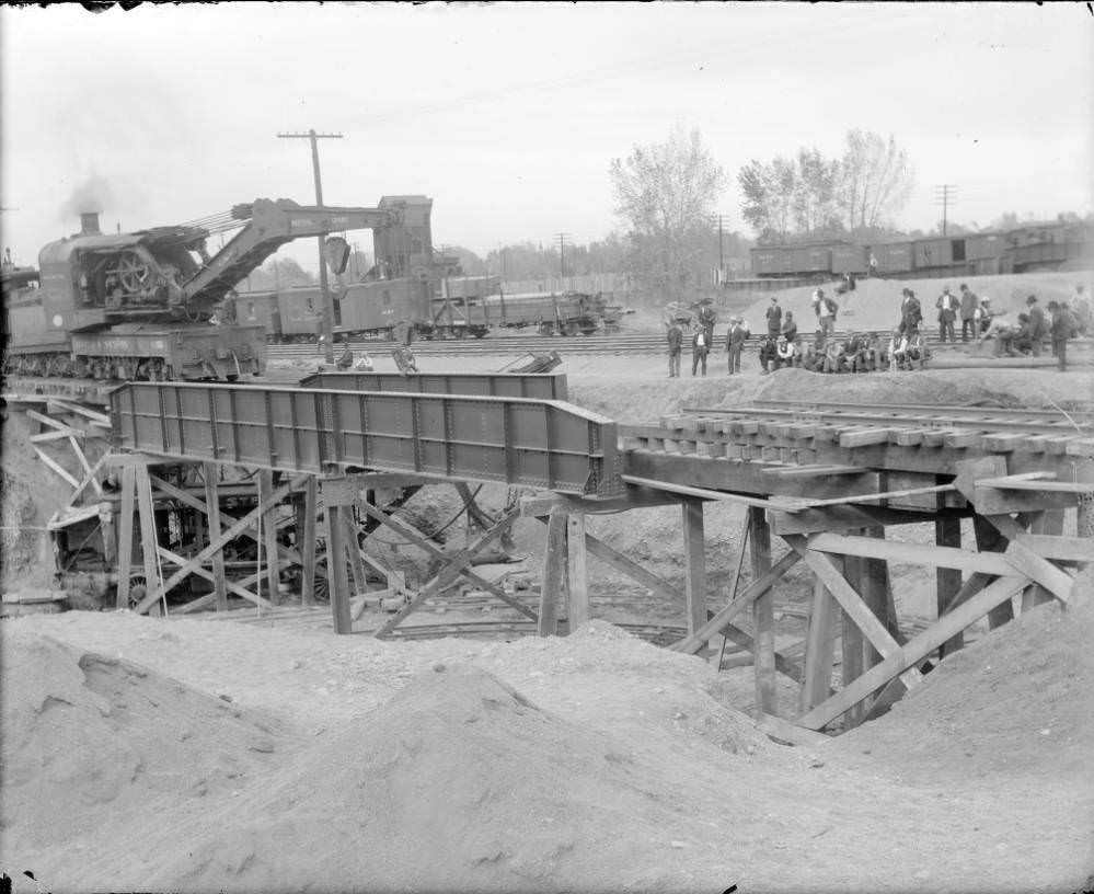#90 Crane from Colorado and Southern Railway works on new bridge over Alameda Avenue, Denver, spectators and boxcars in distance, 1909.