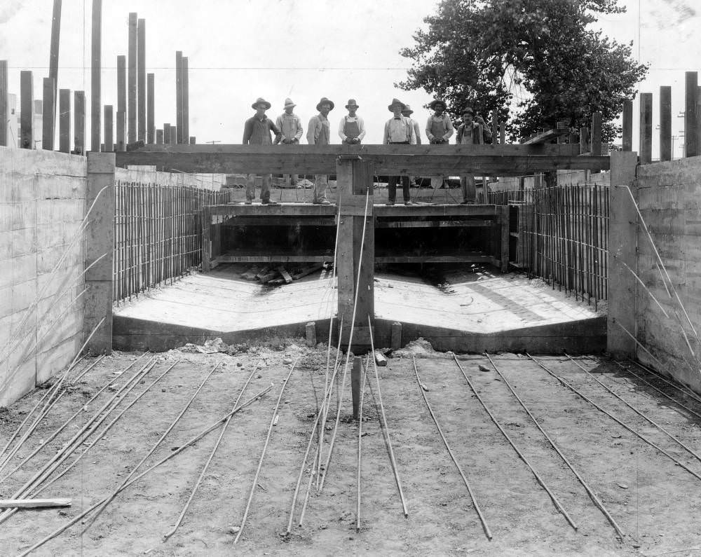 #93 Men pose by concrete forms during flood control construction in Denver, 1900s