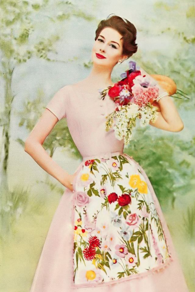 #26 Nancy Berg in a pale pink dress adorned with a flowered chintz apron sparkled with sequins, 1957.