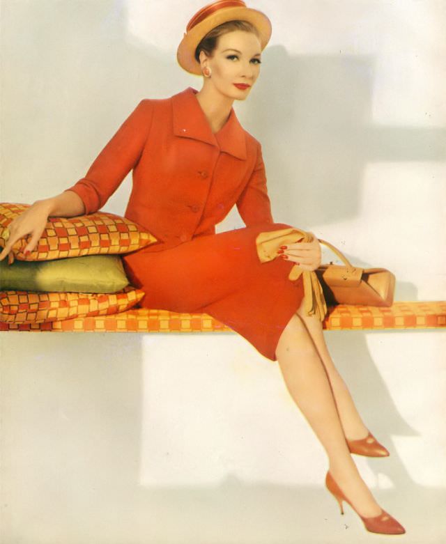 #39 Jessica Ford in a salmon-colored wool tweed suit by Handmacher, accessorized with a straw hat, handbag, and gloves, 1959.