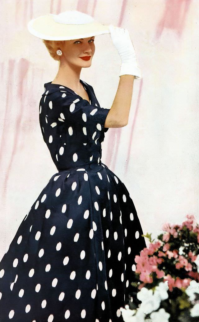 #8 Sunny Harnett in a navy and white saucer-dot silk dress with a bell skirt by Kaspar, and a straw sailor hat by Sally Victor, 1954.