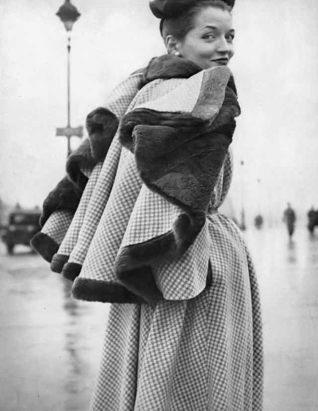 #1 Maxime de la Falaise in a checked wool dress with patent leather belt and detachable nutria-lined cape by Jacques Fath, 1948.
