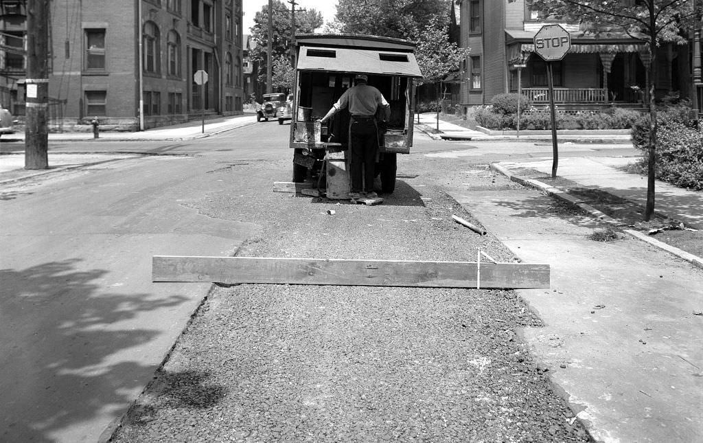 #67 A man operates an asphalt binding machine over a sewer trench, 1-1.5 inches high, at a location 35 feet south of Margaretta Street, 1940