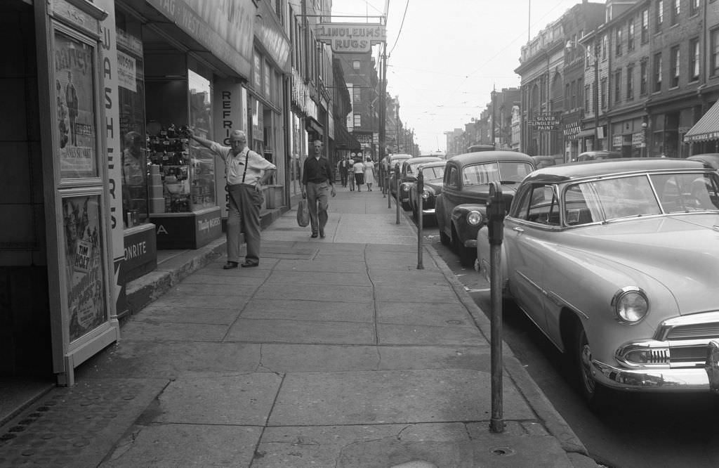 #64 Man leaning on Domestic Appliance Co.’s window next to Acadia Theater on East Ohio Street, 1951.