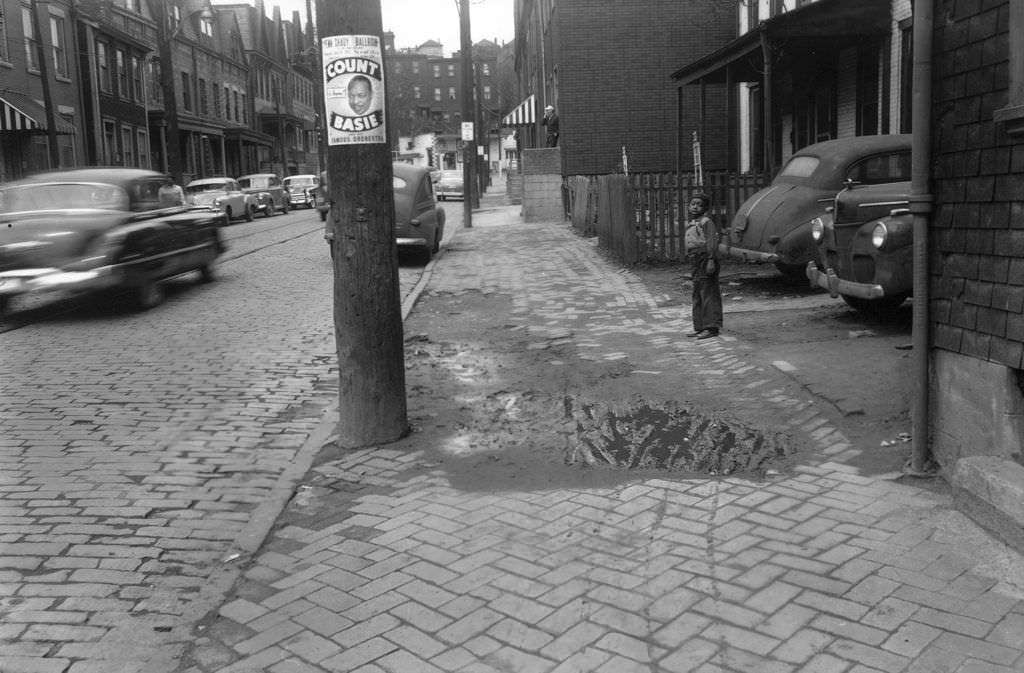 #70 Herron Avenue houses with boy near Count Basie poster, 1953.
