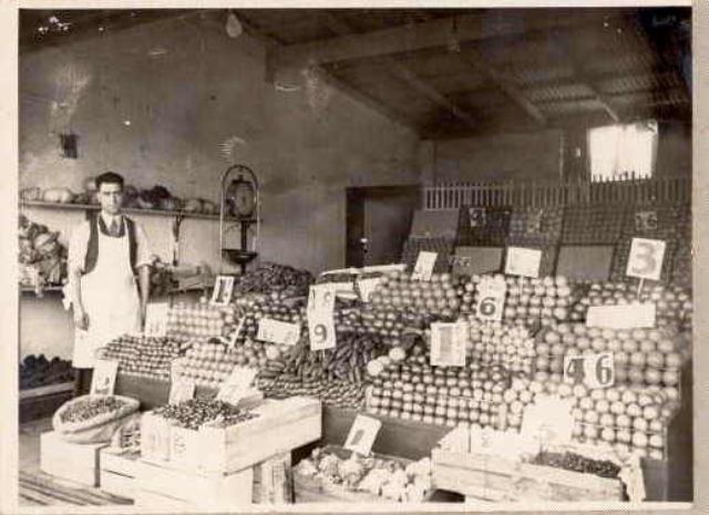 #43 A fruiterer in a white apron in his greengrocer shop