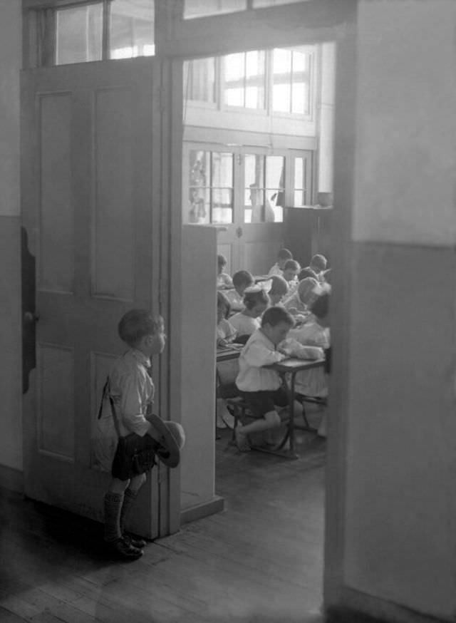 #6 A young Australian boy stares into a classroom already full of students, circa 1930