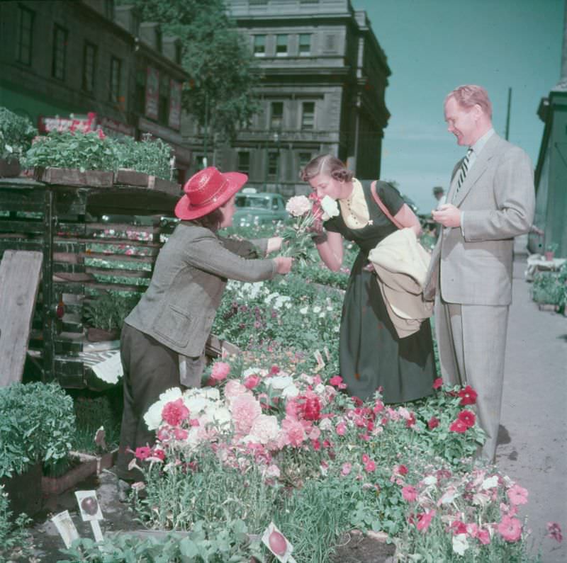 #2 A woman smelling some flowers offered by a vendor at the Bonsecours market.