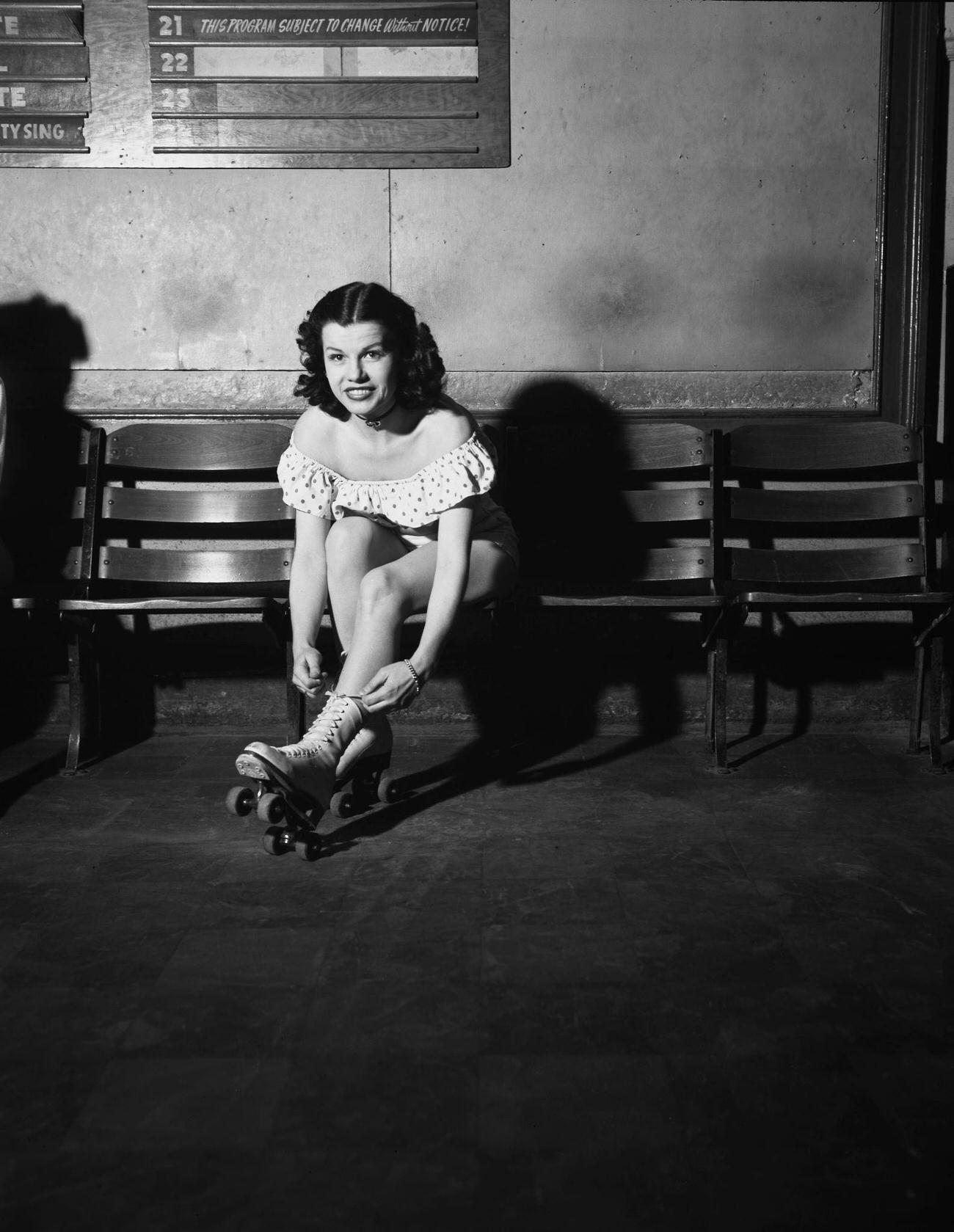 #36 Young Woman Putting on Roller Skates at a Rink, USA, circa 1950